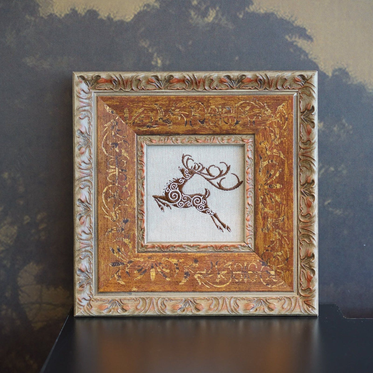 Framed linen embroidery of a leaping stag, used as an example of animal motif wall art styled with restraint.