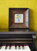 Framed artwork with a lemon floral design on a piano against a green wall