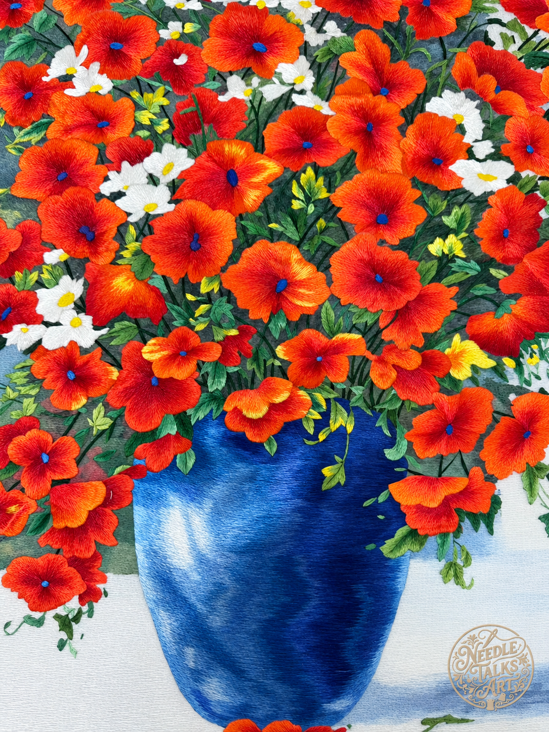 Close-up of red-orange flowers and the shimmering blue vase in The Joy of Blooming silk embroidery.