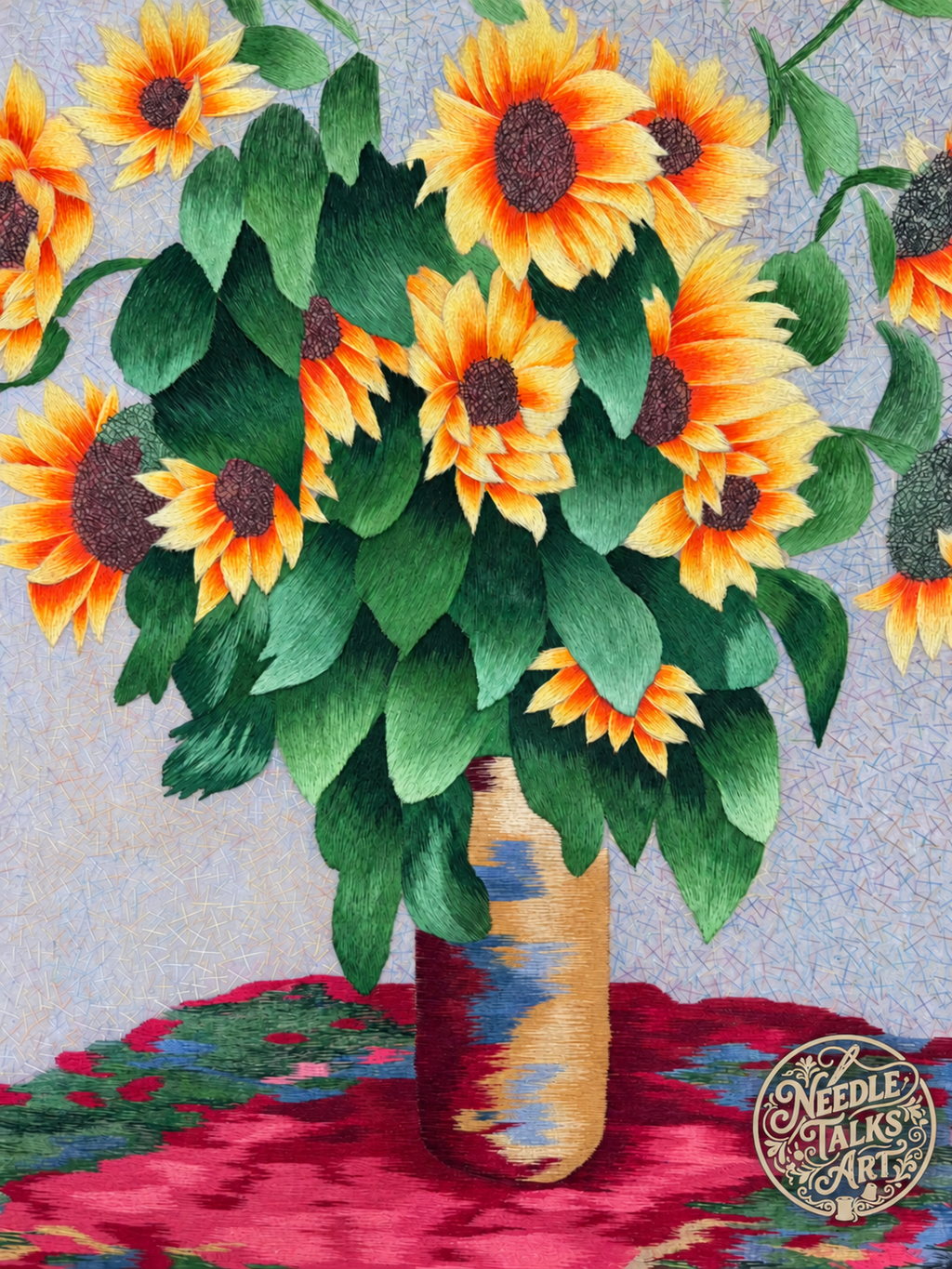 Close-up of sunflower silk embroidery with dense green foliage above a tall vase and red tabletop.