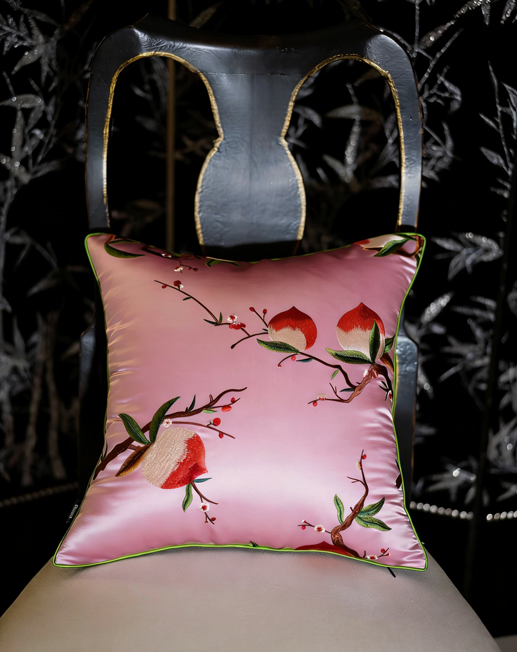 Decorative pillow with floral design on a chair against a dark background