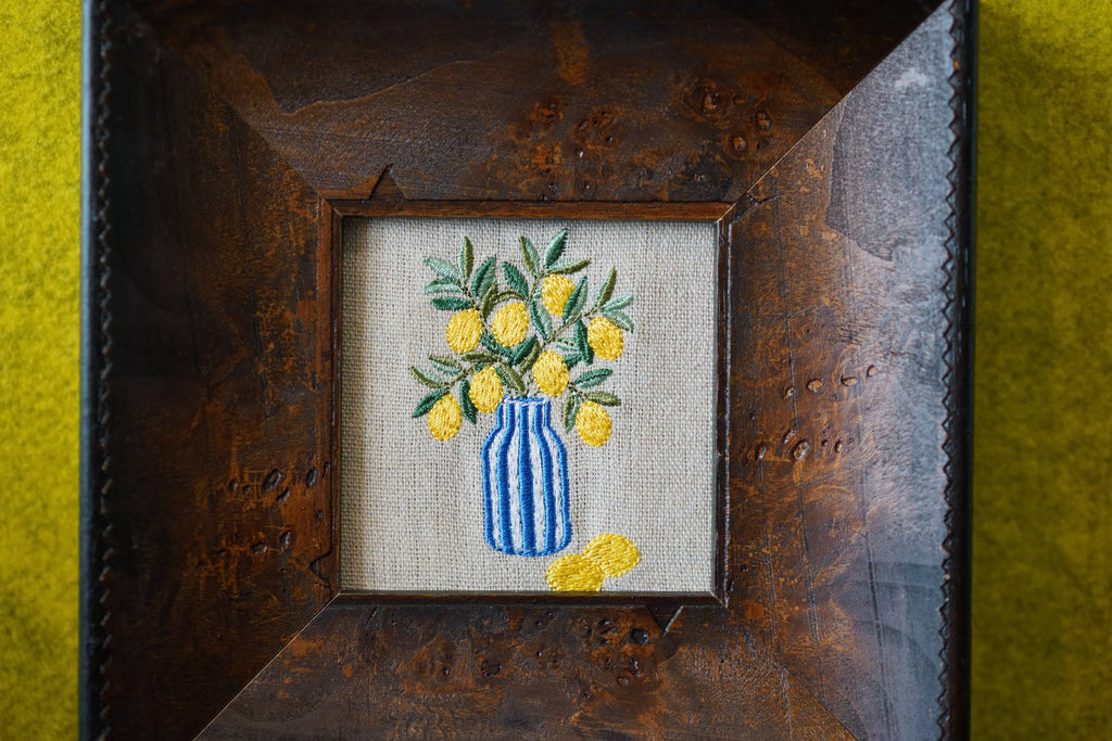 Its cheerful yellow lemons and rich wood frame create a warm focal point that instantly brings life and character to any room