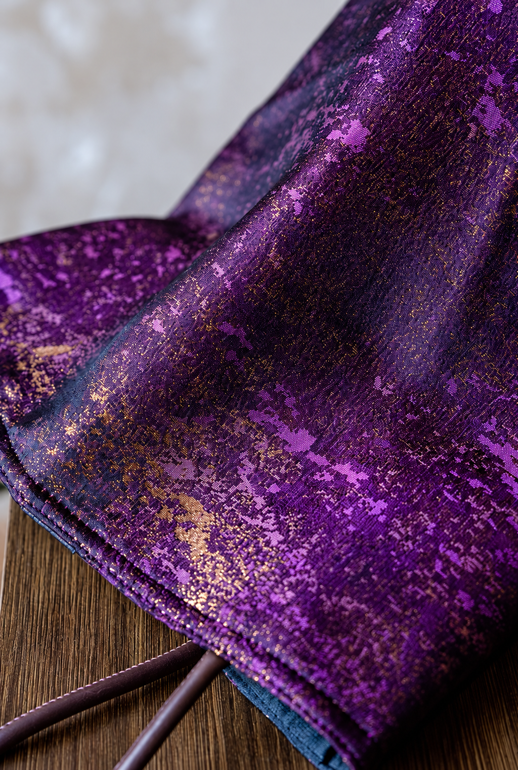 Close-up of Violet Dusk purple and gold jacquard fabric, showing the stitched edge and brown handles.