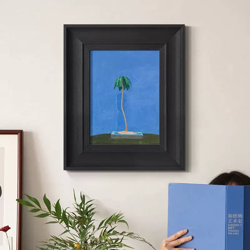 Framed palm tree art print in a bold black frame. A versatile piece of wall art for modern interior design, suitable as a bir