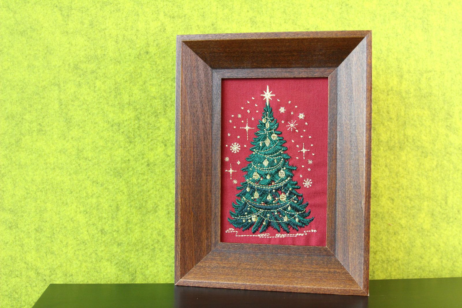 Brown wood framed Christmas tree embroidery displayed on a table