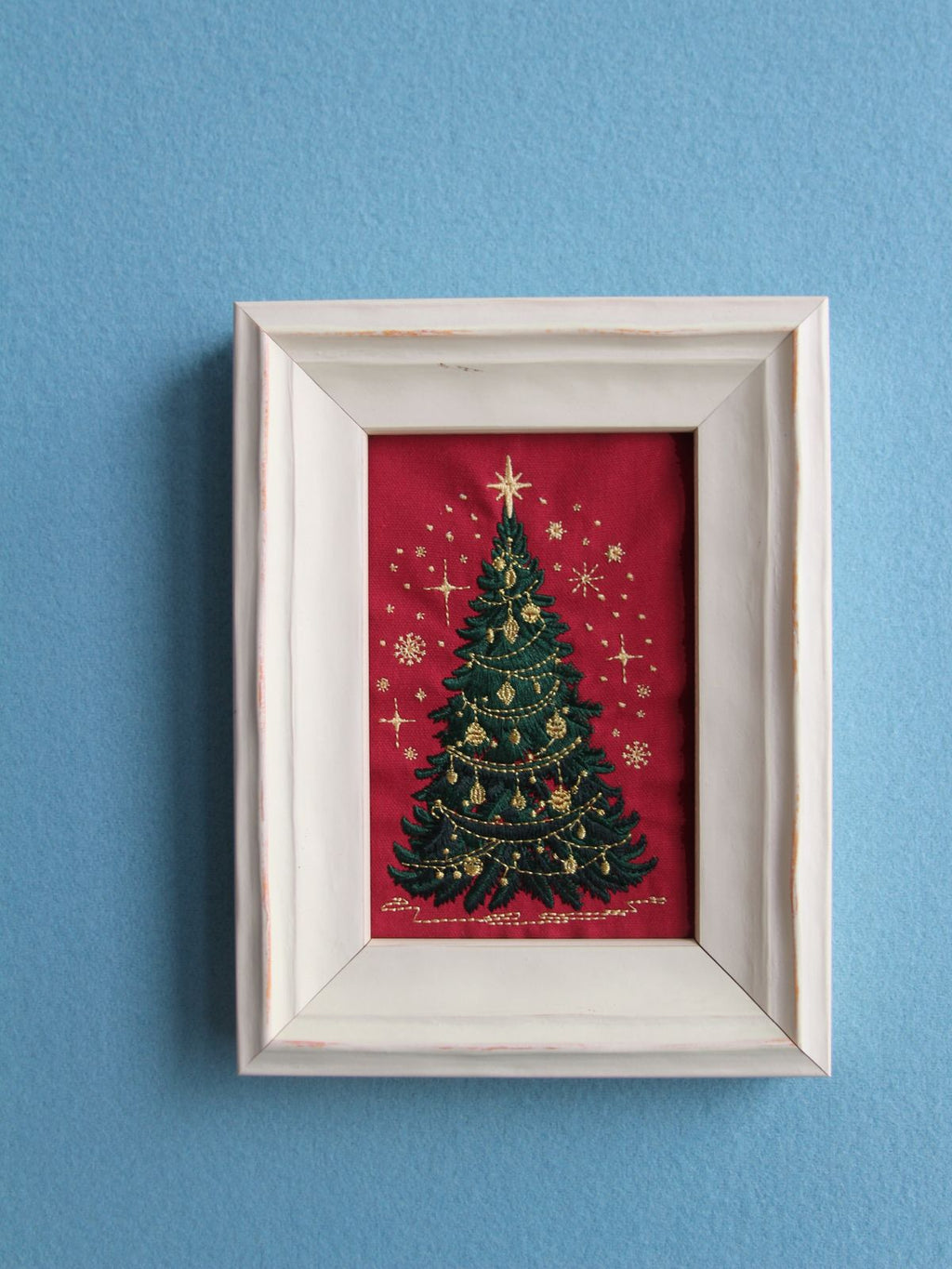 Glittering Christmas tree embroidery in a white wood frame, front view