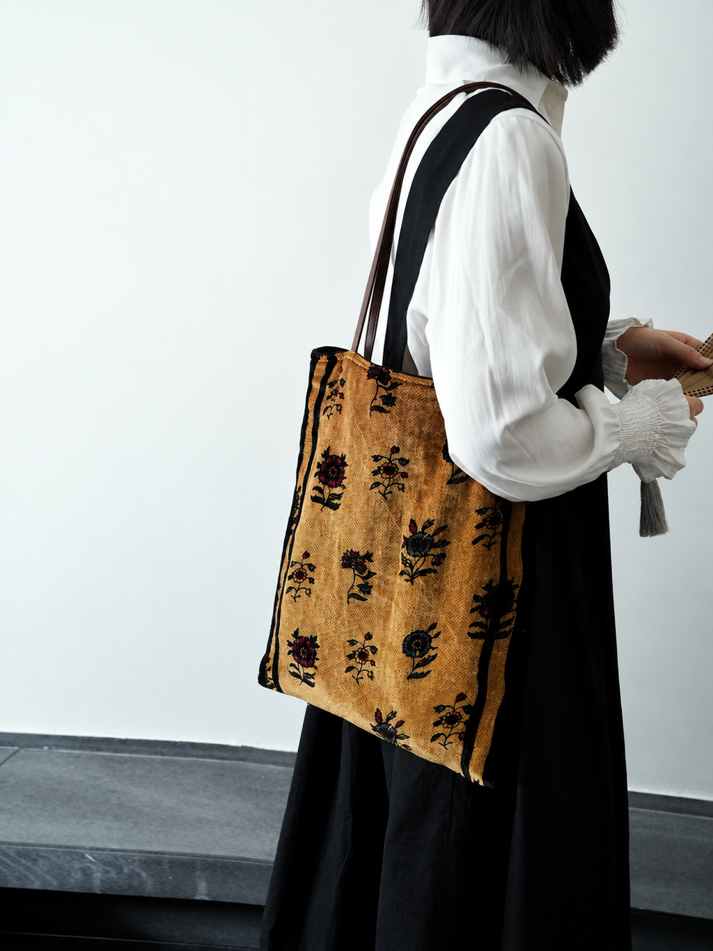 Side view of a golden floral silk velvet tote bag worn over the shoulder.
