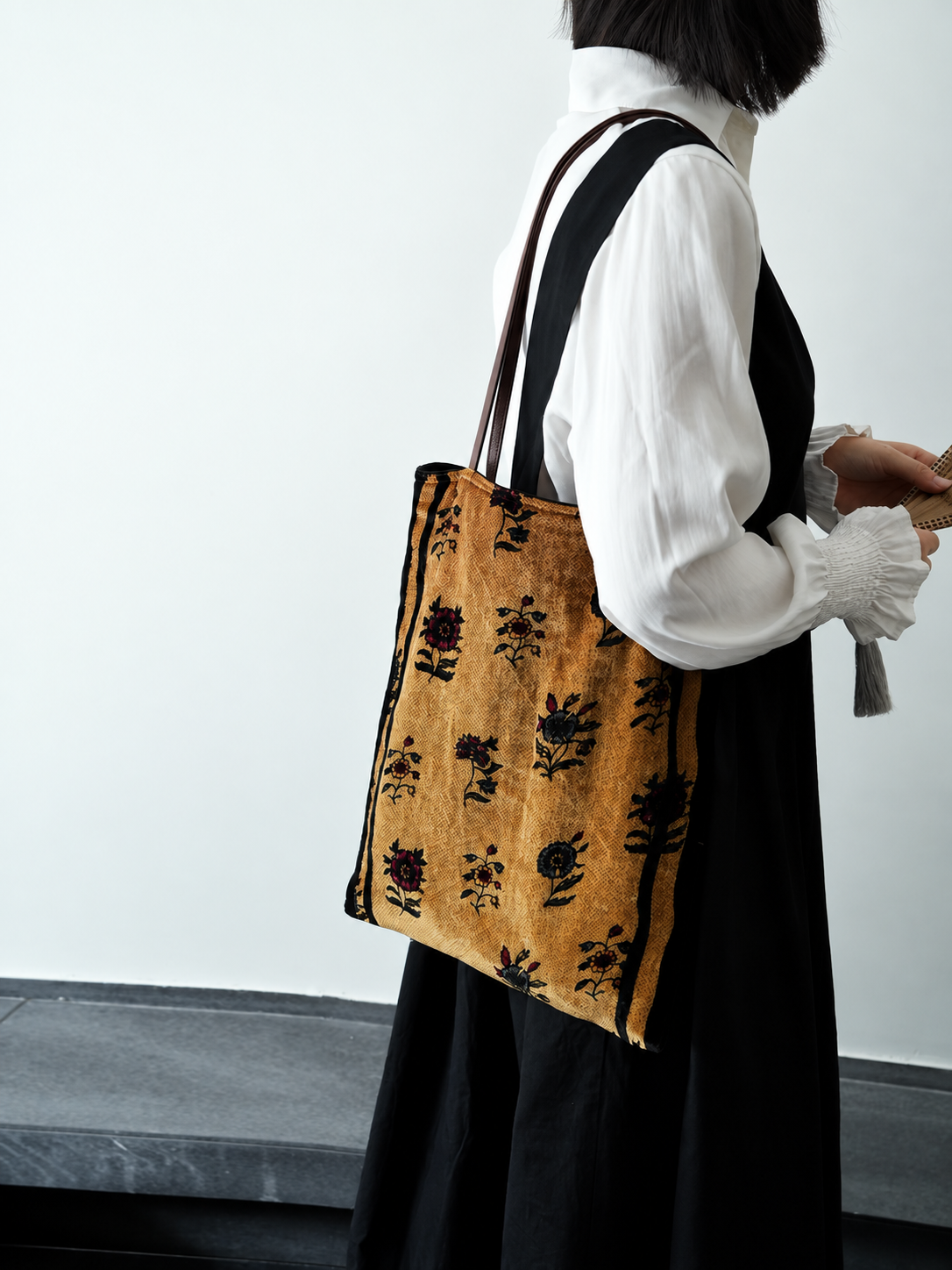Side view of a golden floral silk velvet tote bag worn over the shoulder.