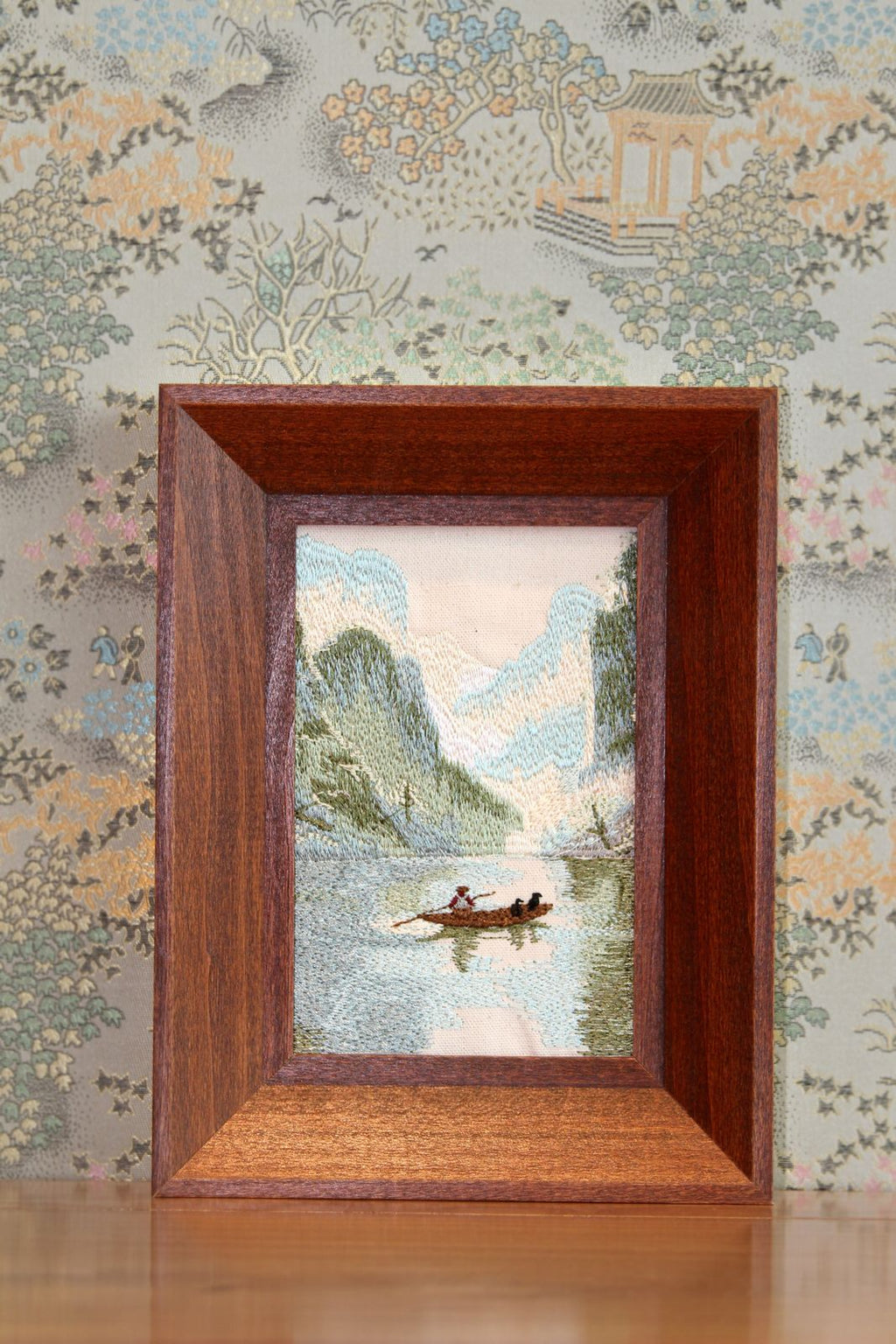 Brown framed Guilin river landscape embroidery displayed on a tabletop