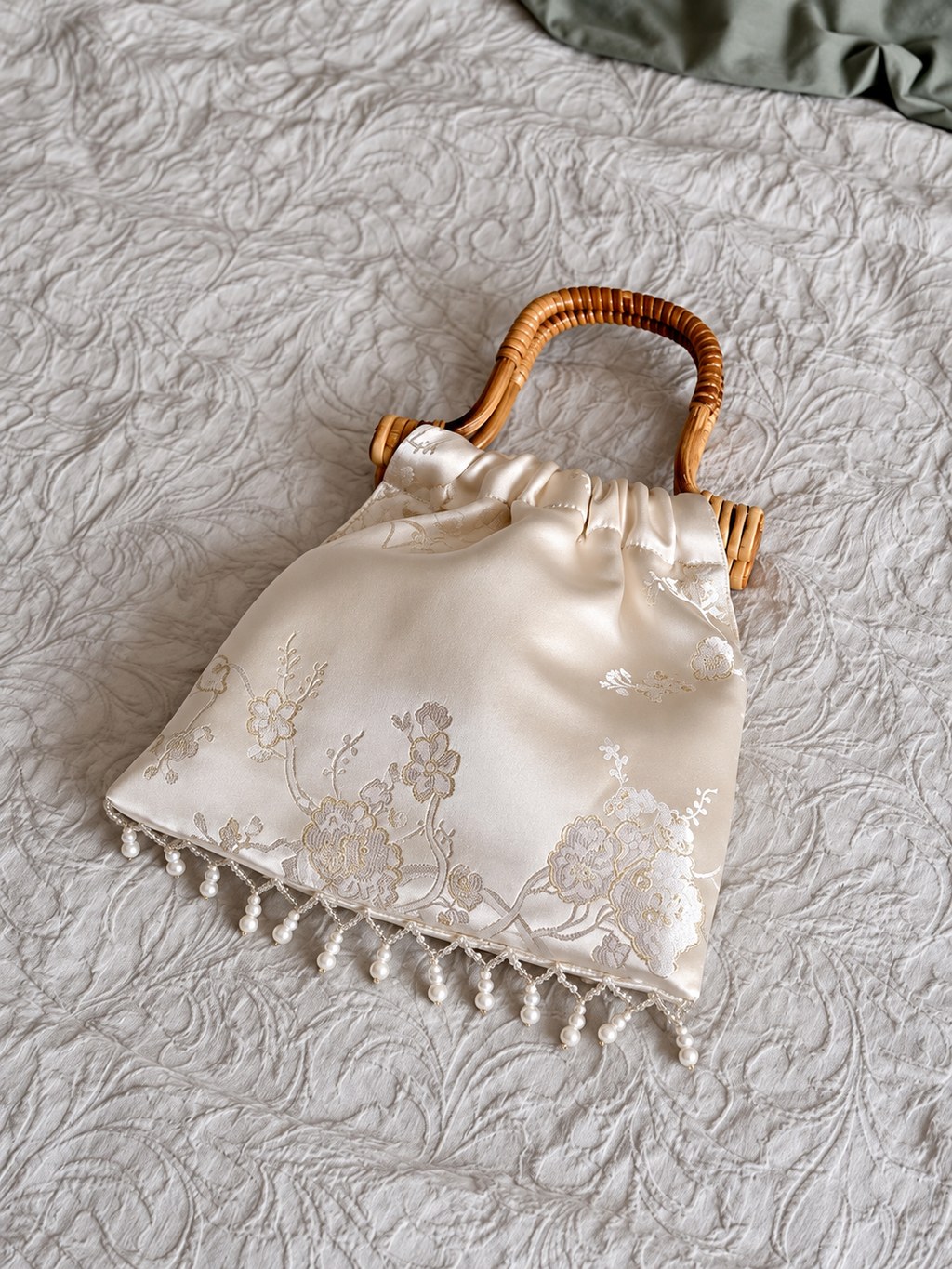 Ivory floral jacquard handbag flat lay showing pearl fringe and woven handle.