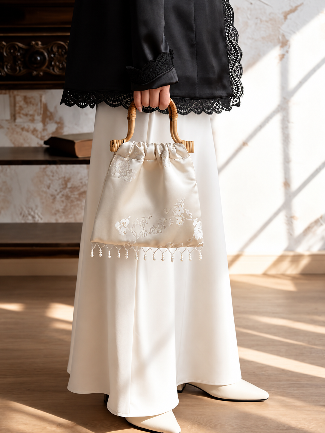 Ivory pearl-fringe handbag carried by hand for scale.