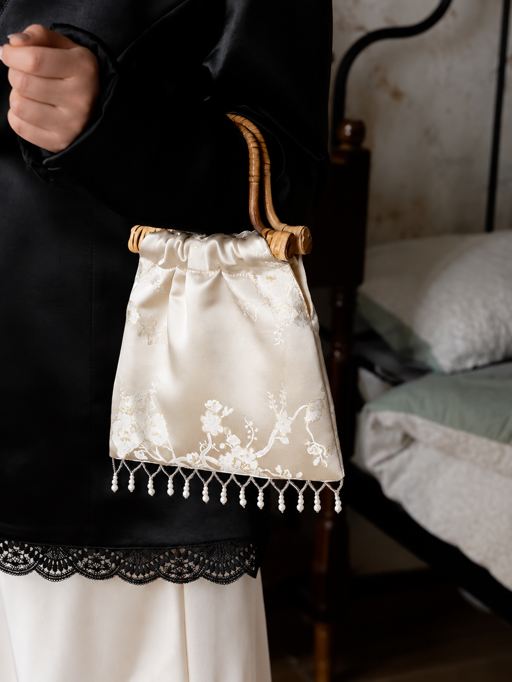 Ivory jacquard rattan-handle handbag worn with black and white clothing.