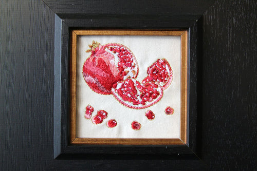Close view of red pomegranate embroidery with shimmering gold-thread details
