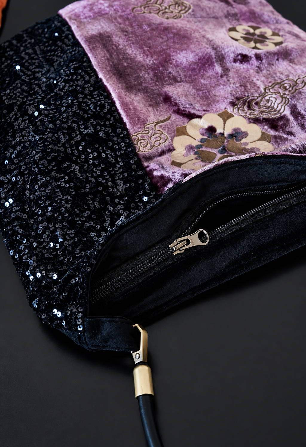 Close-up of the purple velvet and black sequin bag zipper and brass-tone strap hardware.