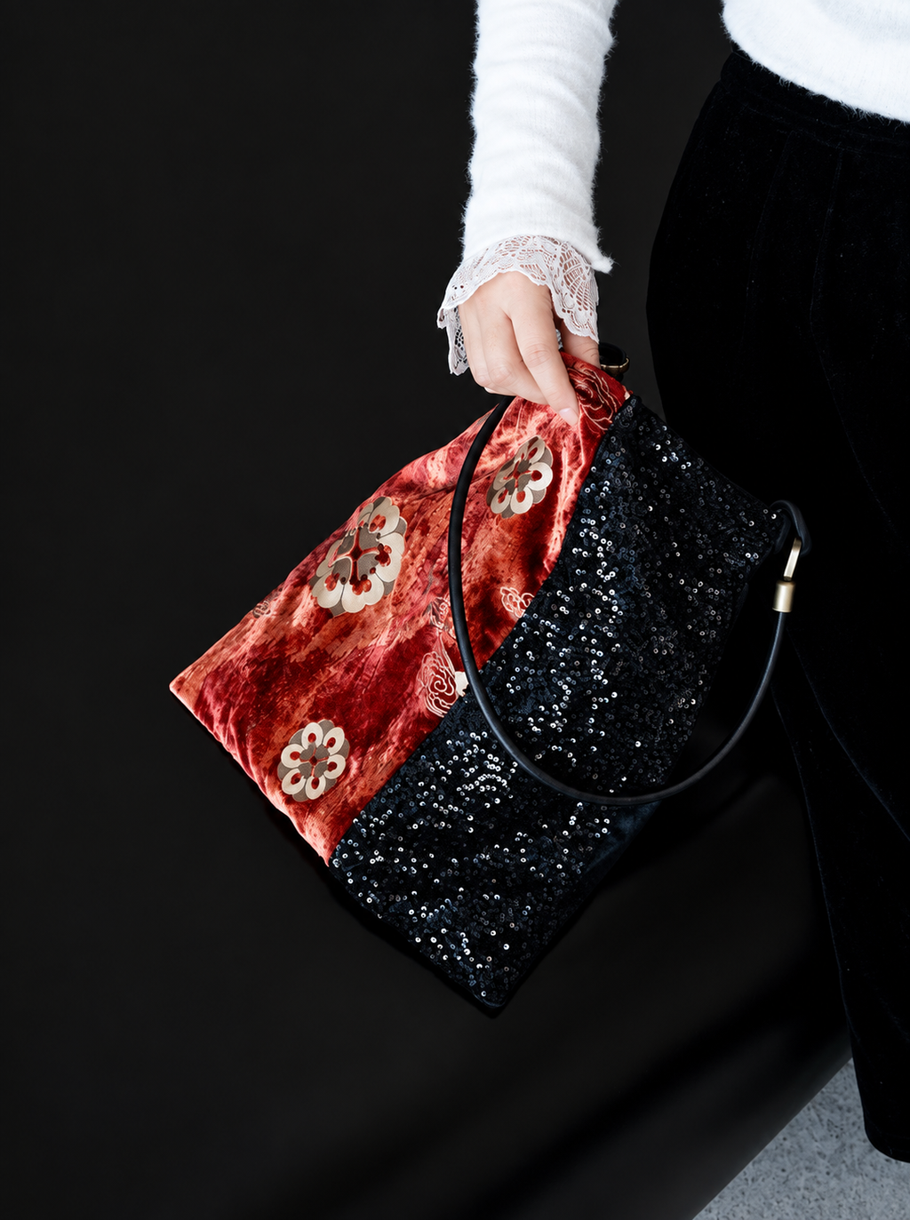 Close view of a red floral velvet and black sequin shoulder bag being carried.