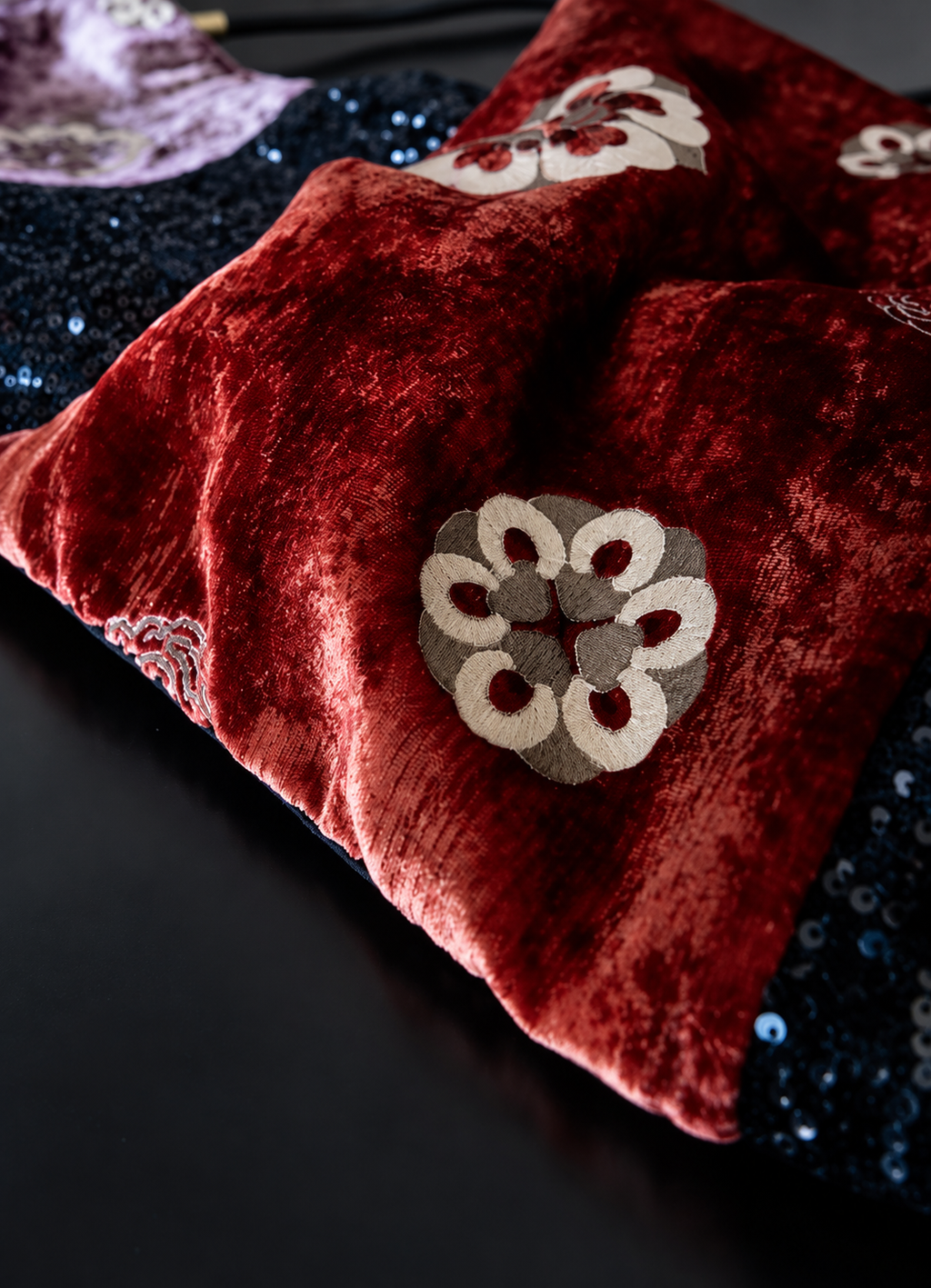 Close-up of red crushed velvet, floral appliqué and black sequin textures.