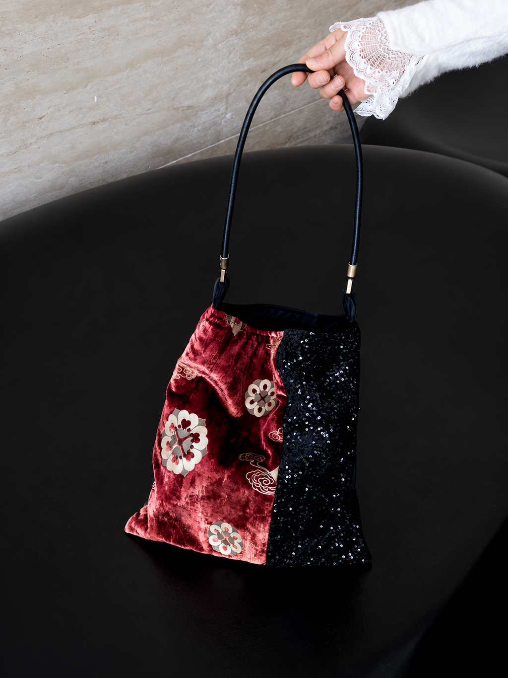 Red floral velvet and black sequin shoulder bag shown by its black leather strap.