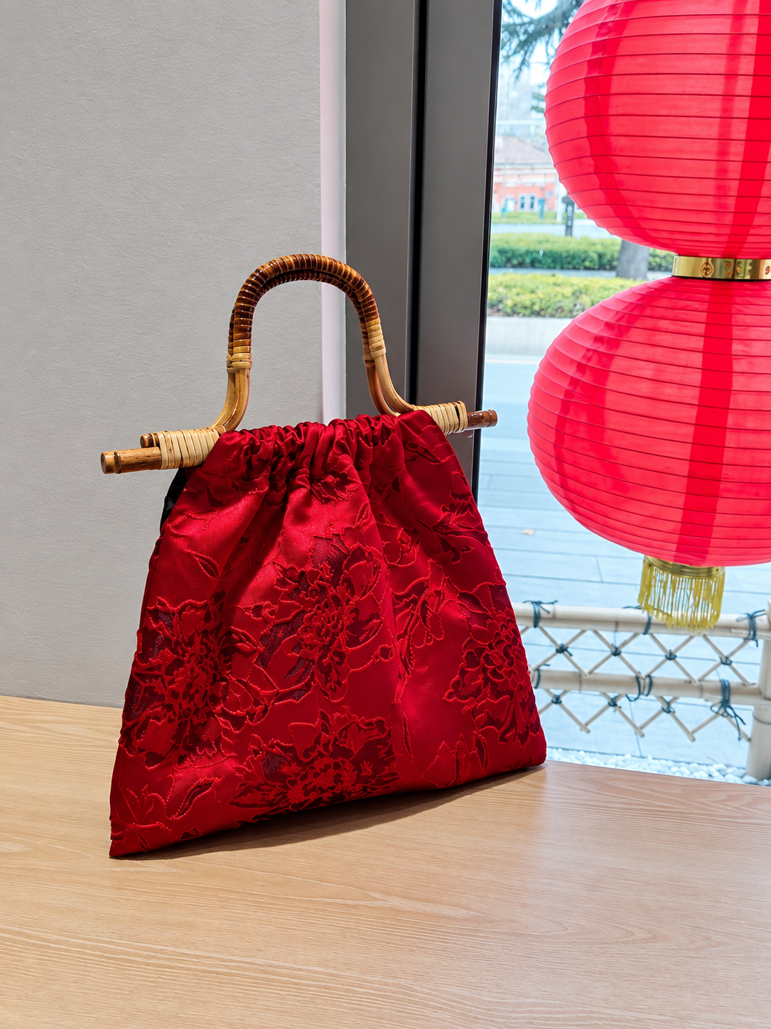 Rear view of the crimson floral jacquard handbag with bamboo handle.