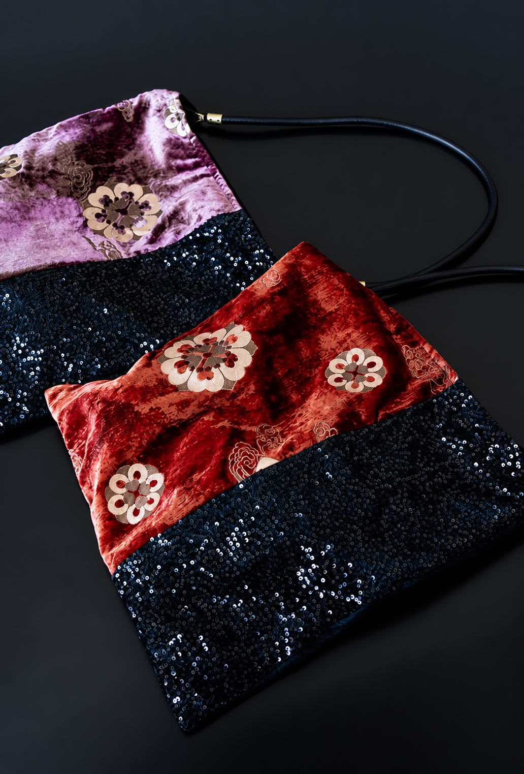 Red and purple floral velvet shoulder bags with black sequin panels arranged together.