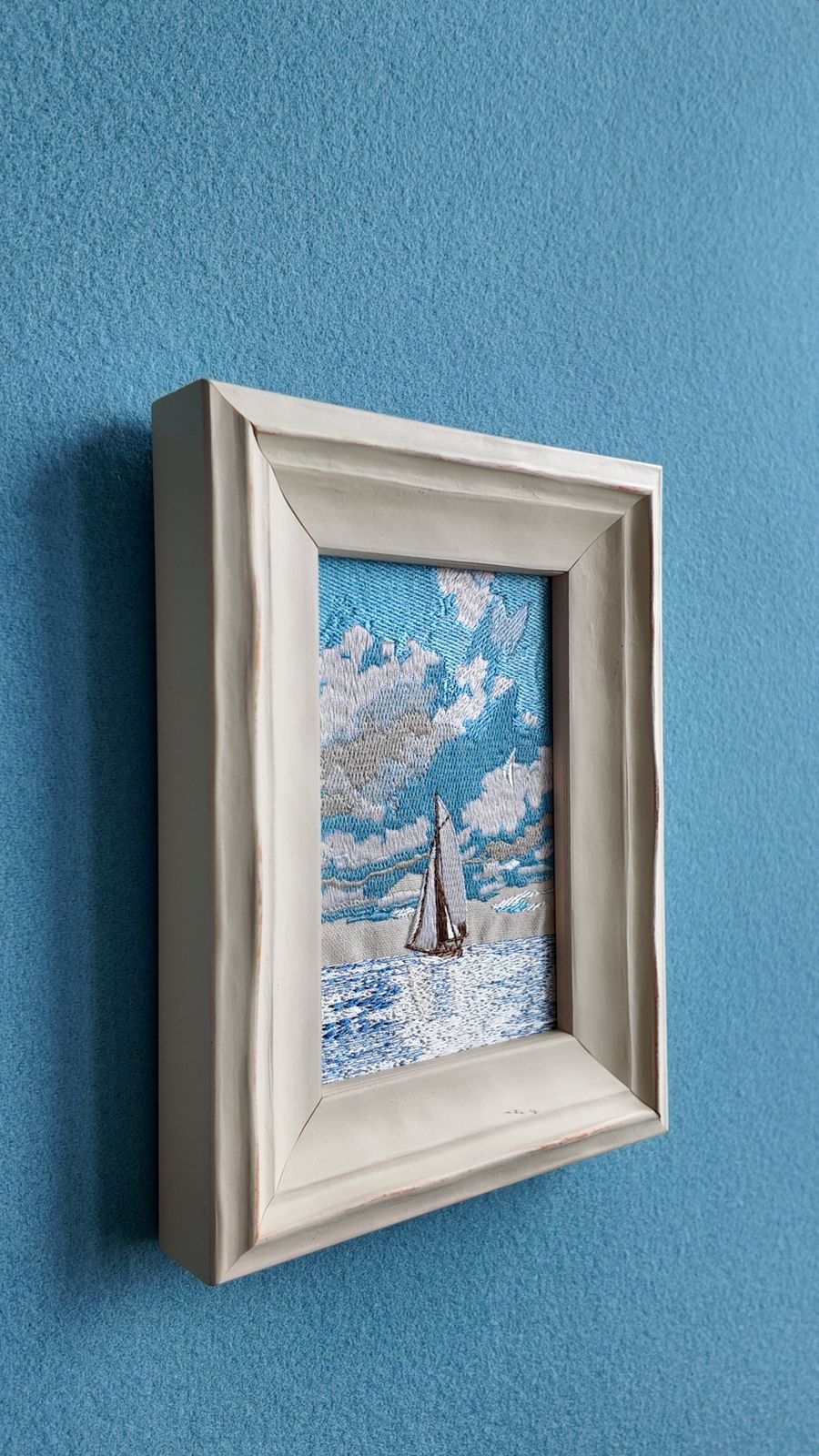 Side view of the framed sailboat embroidery showing the frame depth