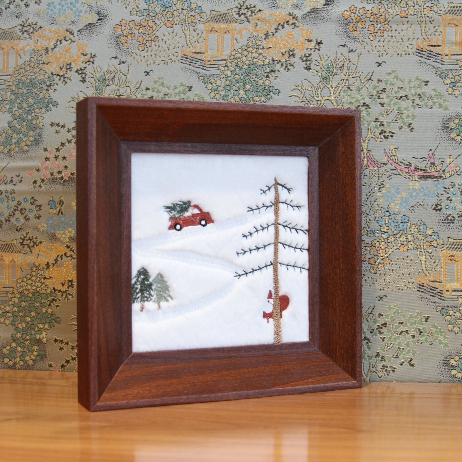 Brown wood framed Christmas embroidery styled on a table