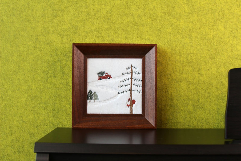 Square framed Christmas embroidery displayed on a tabletop