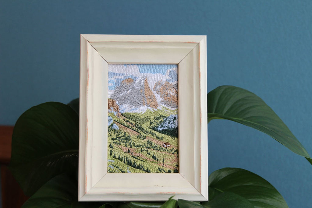 White framed Swiss alpine embroidery styled among green plants