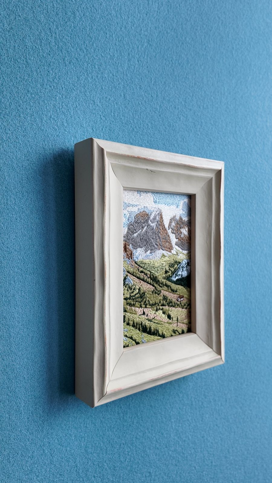 Side view of framed Swiss Alps embroidery showing the frame depth