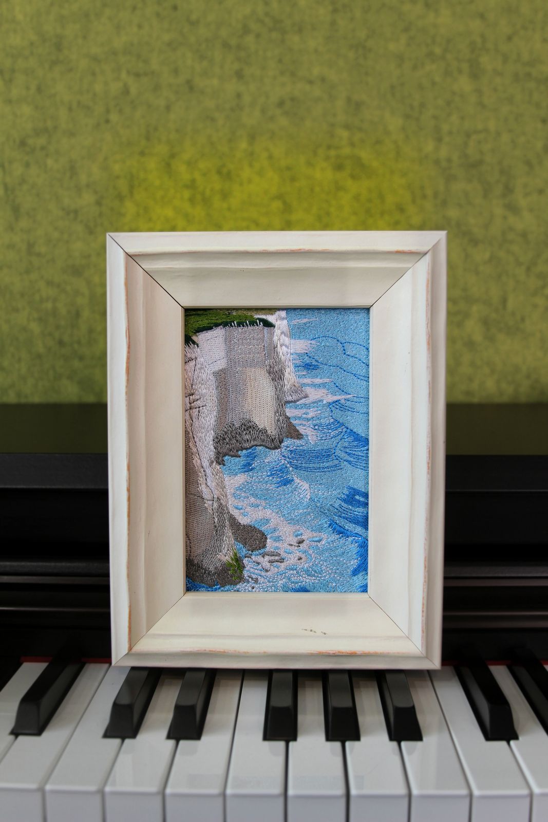 White Cliffs framed coastal embroidery displayed on a piano